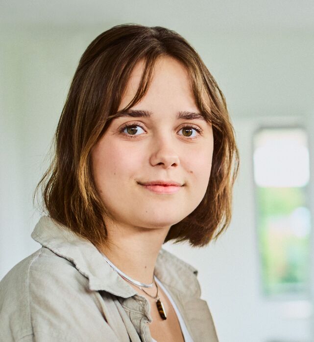 Employee Lisa Grünewald sitting in the office on a desk, smiling