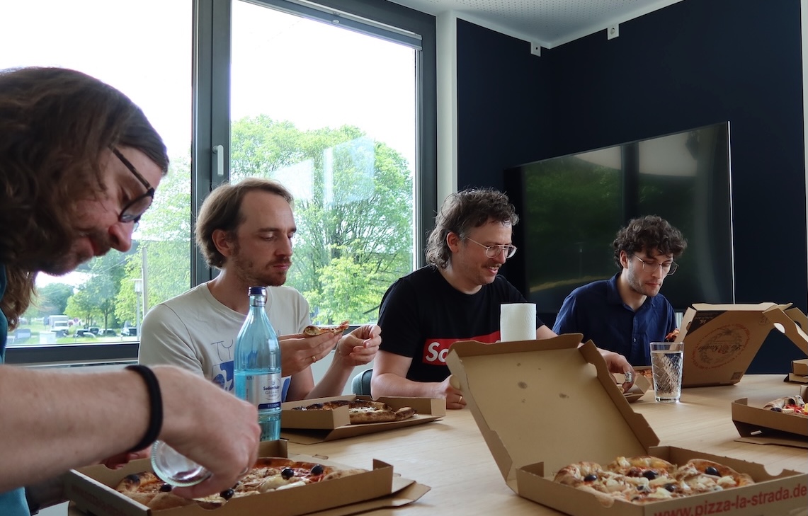 Game Jam lunch: Employees eating pizza together at a big table